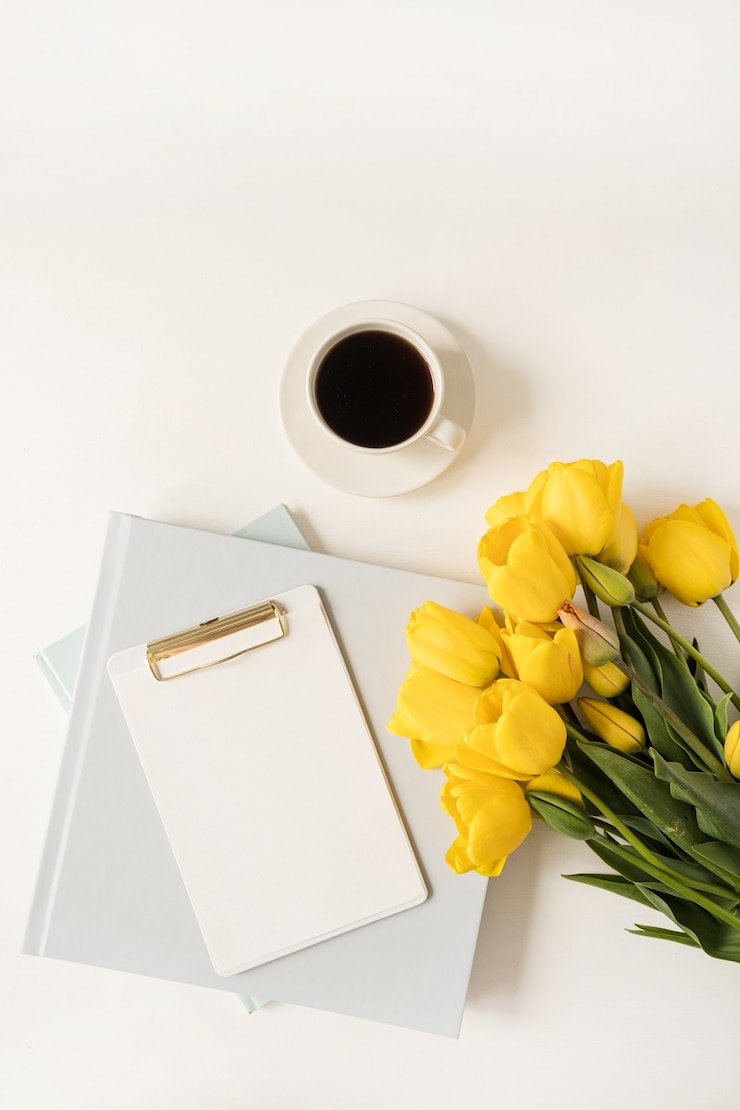 Photo home office table workspace. blank sheet clipboard pad with copy space, coffee cup, tulip flowers on white