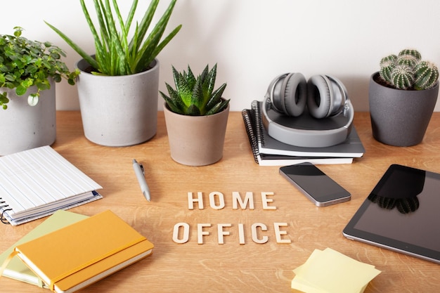 Home office text desk with tablet computer smartphone notebook houseplants working space at home