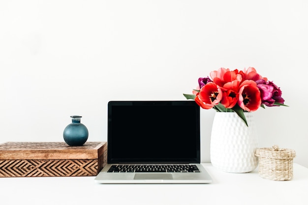 Ministero degli interni con laptop copia spazio, bouquet di fiori di tulipano, decorazioni su bianco