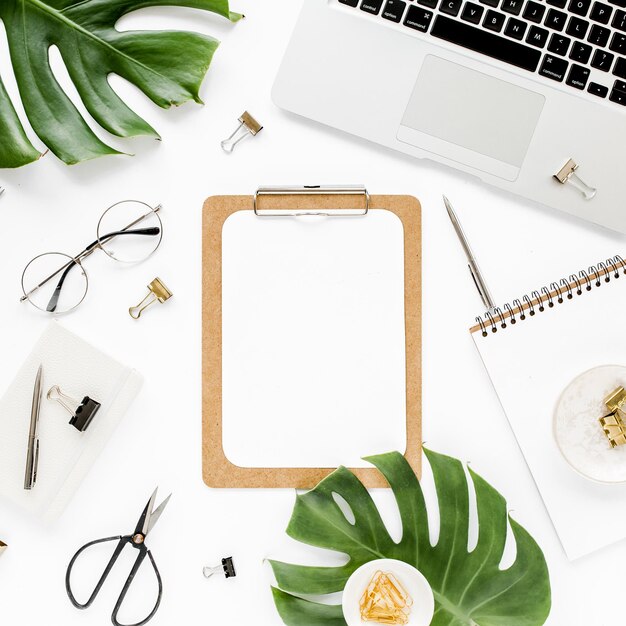 Home office workspace mockup with laptop tropical leaves monstera clipboard notebook and accessories