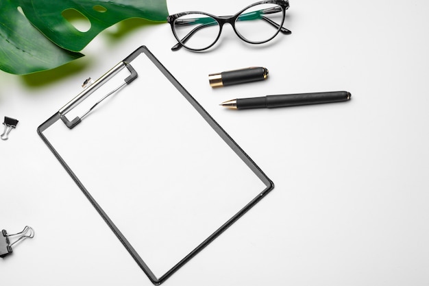 Home office workspace  with clipboard, palm leaf and accessories. Flat lay, top view