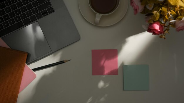 Home office workspace with laptop computer sticky notes decor and sunlight shadow on white table