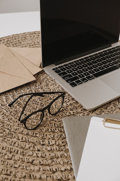 Home office workspace with laptop, glasses, clipboard pad, envelopes.