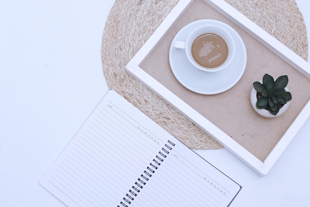 Home office workspace with notebook sheet and cup of coffee in\
a wooden tray. flat lay, top view.