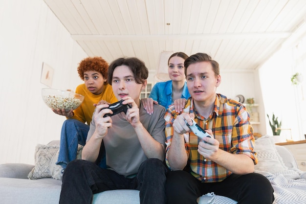 Домашняя вечеринка веселая группа друзей играет в видеоигры дома счастливая разнообразная группа друзей