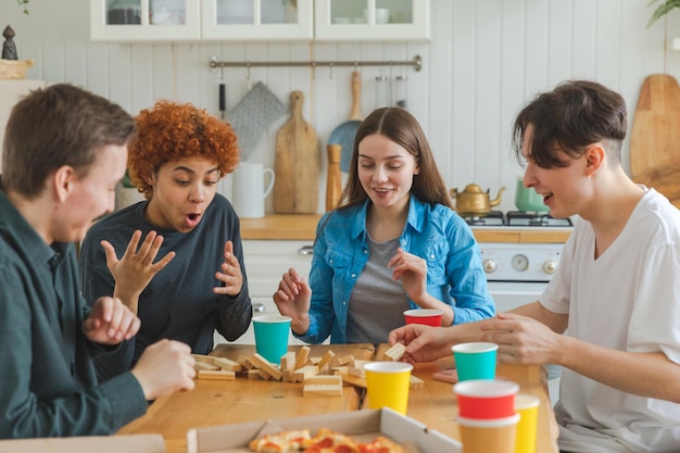 Home party friends spending time together playing in board game crash wooden tower at home happy div