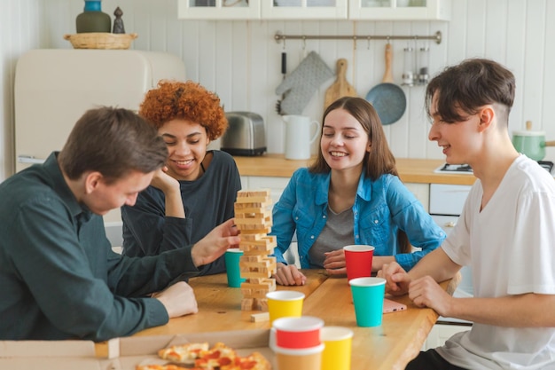 Home party friends spending time together playing in board game crash wooden tower at home happy div