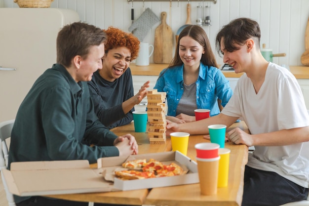 Home party friends spending time together playing in board game crash wooden tower at home happy div