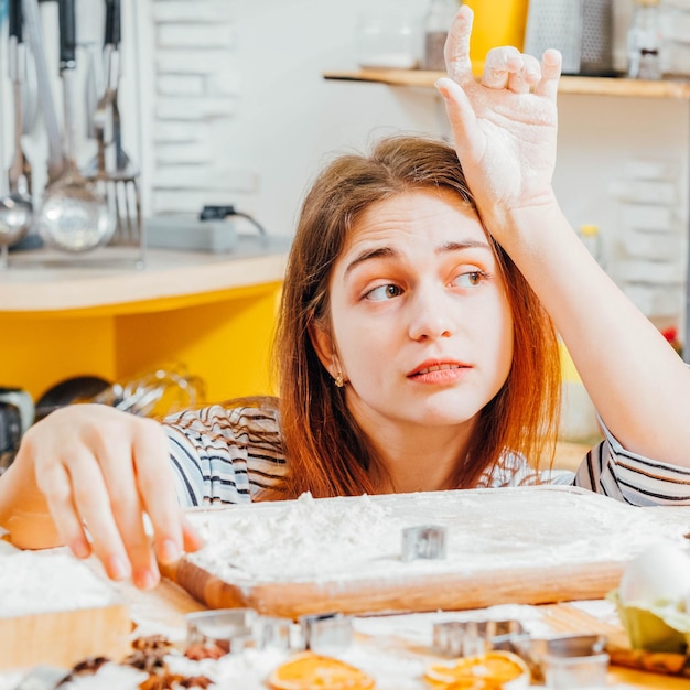 Home pastry cooking Portrait of thoughtful lady sitting in kitchen hands covered with flour waiting for biscuits ready