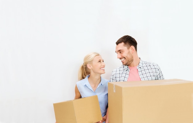 home, people, repair and real estate concept - happy couple holding cardboard boxes and moving to new place