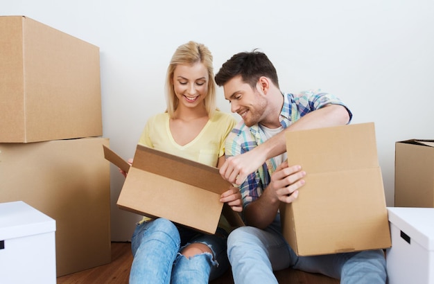 home, people, repair and real estate concept - smiling couple with many cardboard boxes moving to new place