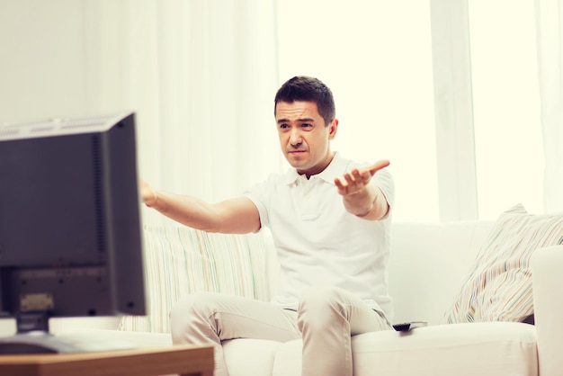 home, people, technology and entertainment concept - disappointed man watching sports on tv and supporting team at home