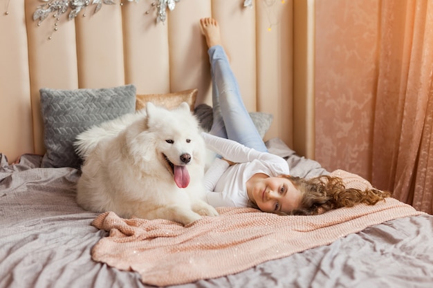 Home portrait of cute child hugging with dog on the sofa