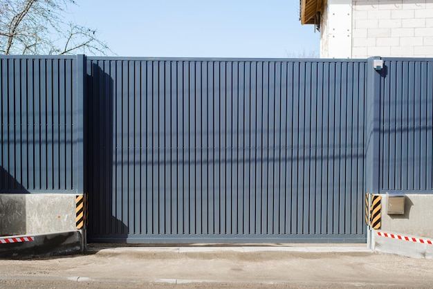 Foto protezione e sicurezza della casa recinzione in acciaio con profilo metallico esterno cancelli automatici scorrevoli e fondamenta in cemento alto all'aperto
