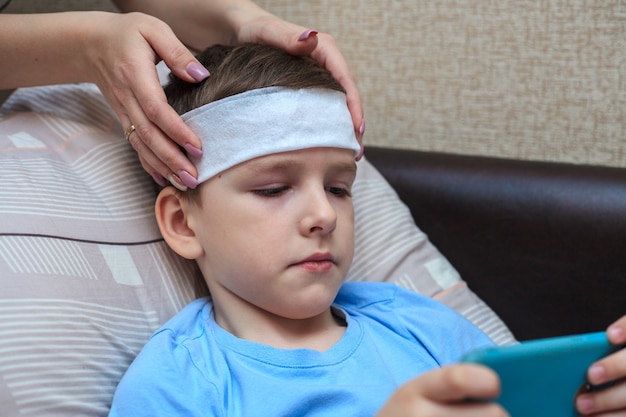 Home quarantine. A wet towel on the forehead of a child. Headache and fever in a boy.