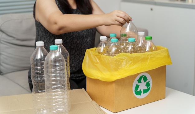 Home recycle eco green zero concept Vrouw gooit lege plastic fles in de prullenbak met gele vuilniszakken thuis