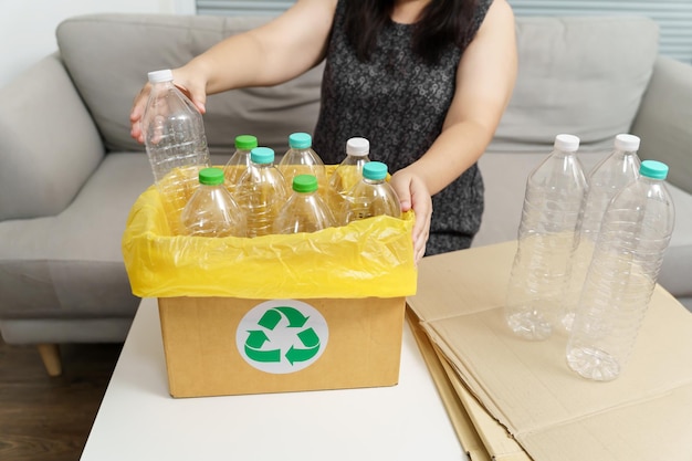 Home recycle eco groen nul concept Vrouw gooit lege plastic fles in de prullenbak met gele vuilniszakken thuis