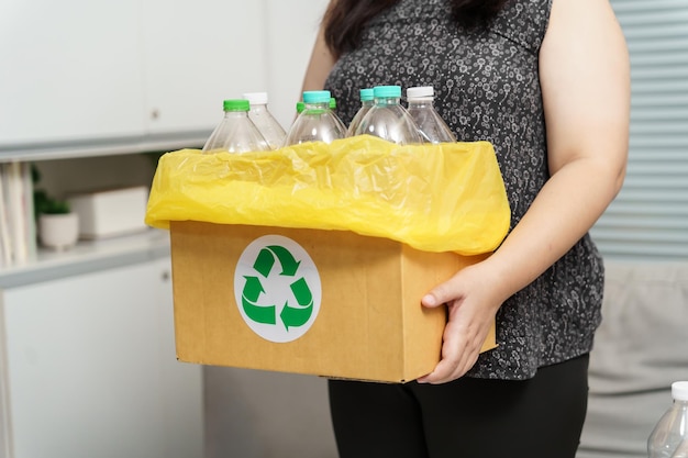 Home recycle eco groen nul concept Vrouw gooit lege plastic fles in de prullenbak met gele vuilniszakken thuis
