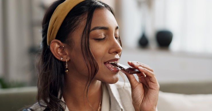 Photo home relax and woman with chocolate bar candy and eating with dessert hungry or sugar person apartment or girl on a sofa smile or sweet treats with a snack nutrition or diet plan with cacao