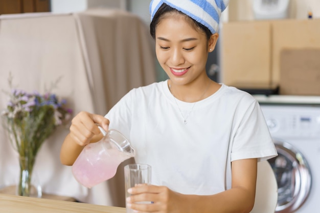 ホーム リラクゼーション コンセプト ターバンでシャワーを浴び、水差しからグラスに水を注ぐ若い女性