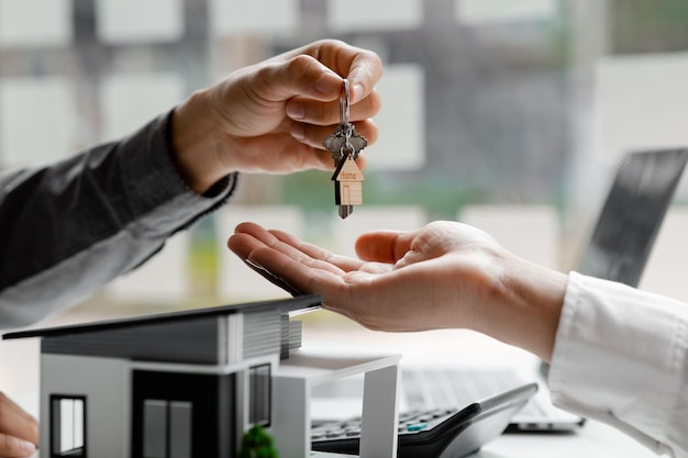 A home rental company employee is handing the house keys to a customer who has agreed to sign a rental contract explaining the details and terms of the rental Home and real estate rental ideas