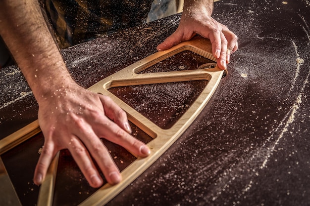 Home repair concepts Close up of a young man carpenter builder equals a wooden bar with a milling machine in the workshop in the background wooden boards