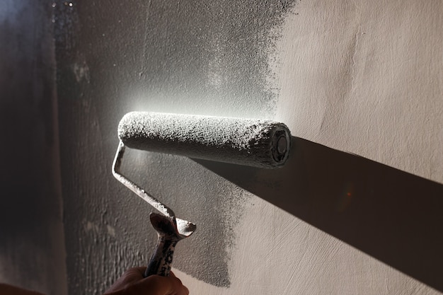 Home repairs. Painting the walls of the room in gray with a paint roller.