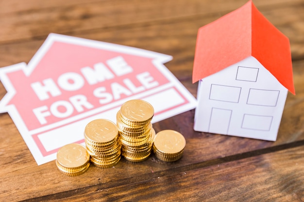 Home for sale icon with stacked coins and house on desk