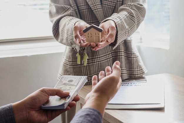 The home saleswoman is delivering a small house model with house keys to the buyer after the purchas