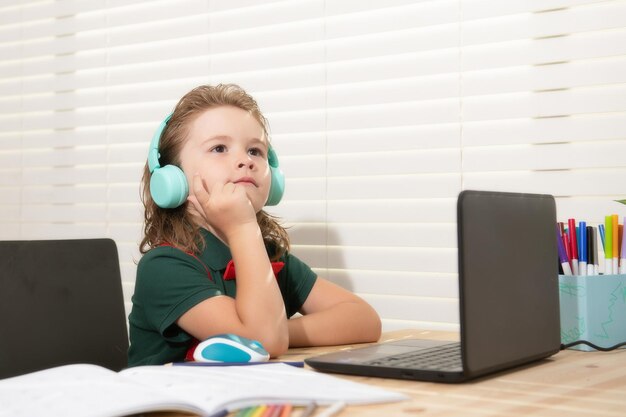 Home schooling concept school boy in headset watching online lesson on laptop