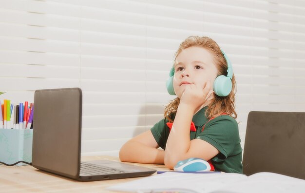 노트북에서 온라인 수업을 보고 있는 헤드셋을 쓴 홈 스쿨링 개념 학교 소년