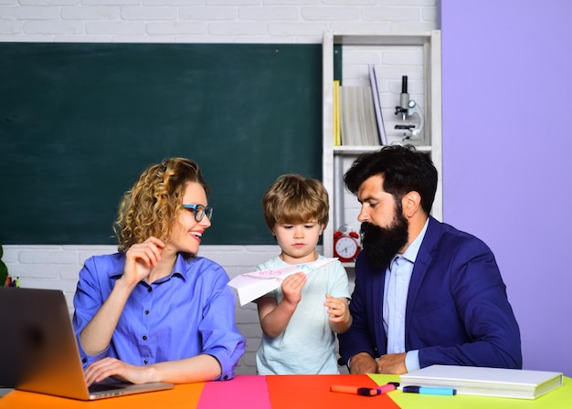Foto lezione di origami di scuola a casa genitorialità mamma e papà aiutano suo figlio allievo carino e i suoi genitori a fare