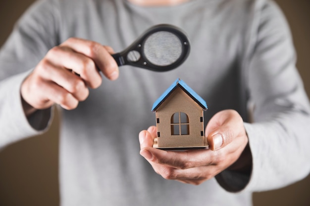 Home search concept. a man holding a magnifying glass and a house