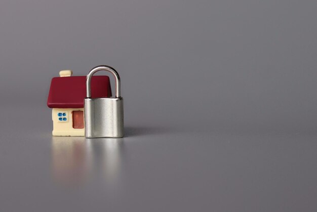 Home security concept toy house and padlock with copy space for
text on grey background