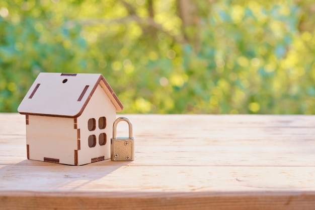 홈 보안 개념: 나무 모델 하우스와 나무 표면에 자물쇠.