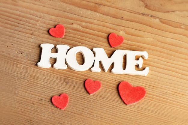 A home sign with red hearts on a wooden background with copy space