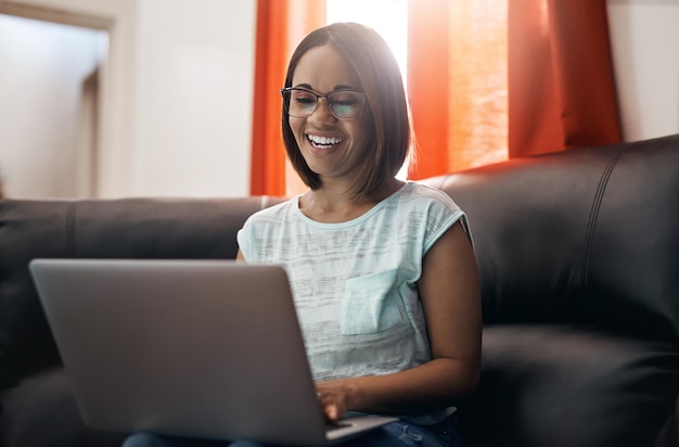 Home smile and woman with a laptop couch and typing with connection network and online reading Female person freelancer and entrepreneur with pc technology and lady search internet and website