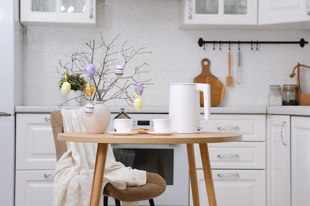 Фото Дома весенний пасхальный дизайн на кухне белый чайник две чашки чайной тарелки с печенье керамической вазой