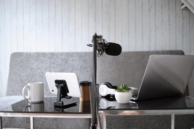 Home studio podcast setting. Microphone, laptop and headphones on the table.