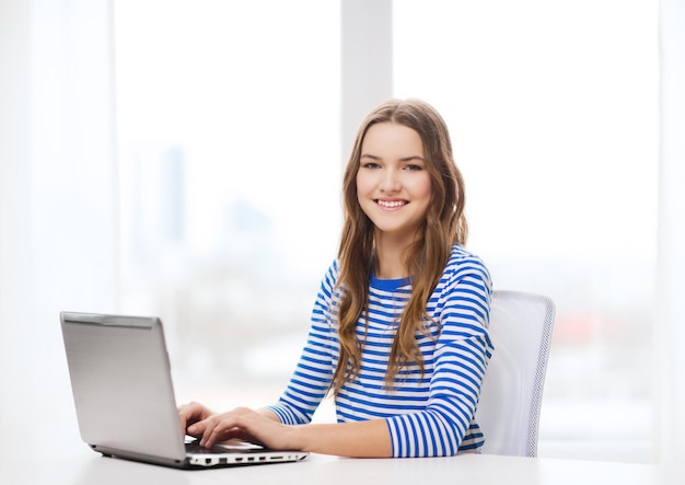 home, technology and internet concept - smiling teenage girl with laptop computer at home