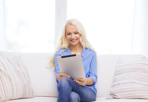 home, technology and internet concept - smiling woman sitting on the couch with tablet pc computer at home