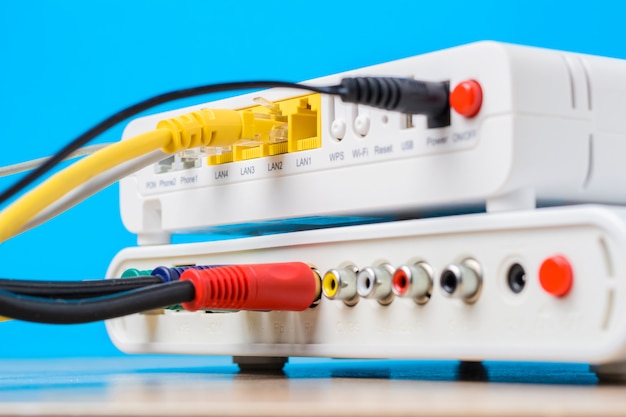 Домашний беспроводной маршрутизатор с кабелями Ethernet подключен на синем фоне, крупным планом