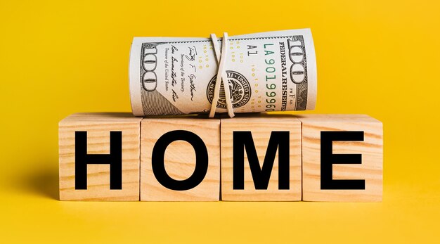 HOME with money on a yellow background. The concept of business, finance, credit, income, savings, investments, exchange, tax