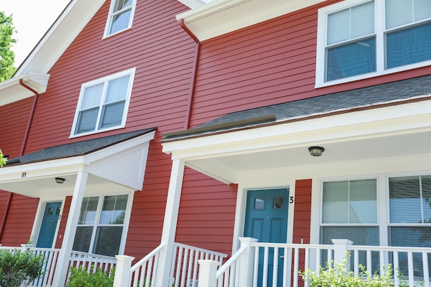 A home with a red wall and white railings and a red door with a white railing.