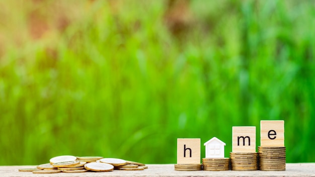 Home word on stack of coins and a pile of golden coins on wooden table