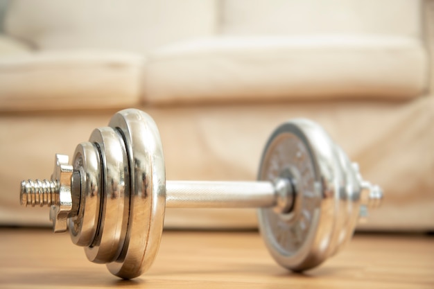 Home workout weight training with dumbbell concept and couch background.