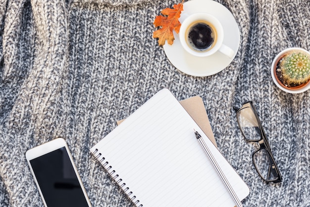 Home workplace with coffee cup on knitted plaid