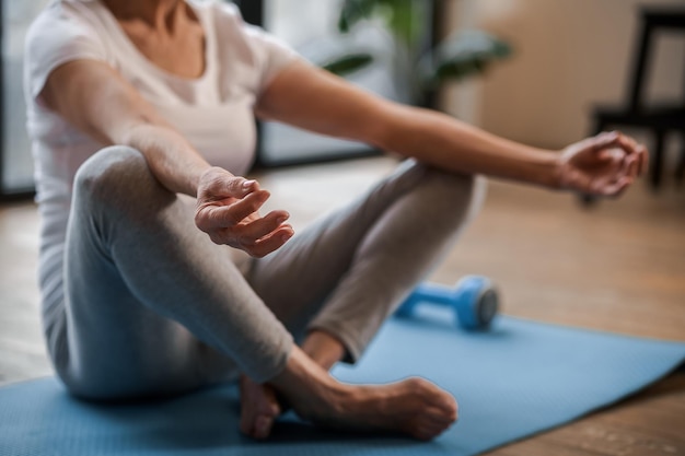 Home yoga. senior woman sitting on the floor ain a lotus pose