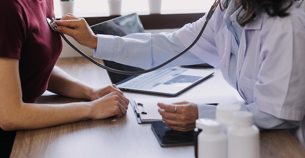 Photo homecare nursing service and elderly people cardiology healthcare close up of young hispanic female doctor nurse check mature caucasian man patient heartbeat using stethoscope during visit