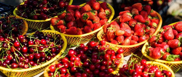 Homegrown berries. Cherries and strawberries in baskets for sell. Farm market. Summer harvest. Red ripe berries. Juicy berries from garden. Buy fresh fruits. Organic berries. Healthy delicious snack.